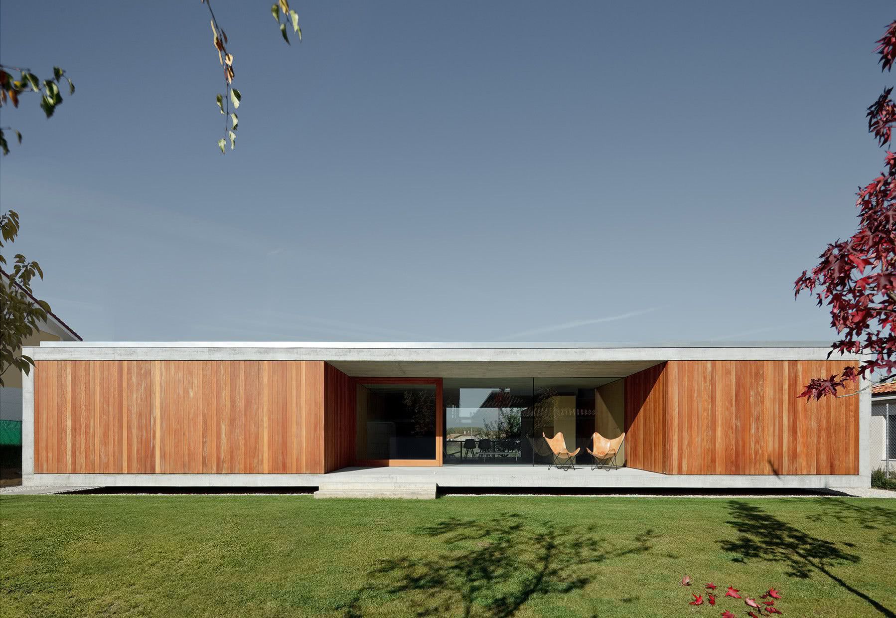 Casa térrea moderna de concreto e revestimento frontal de madeira.
