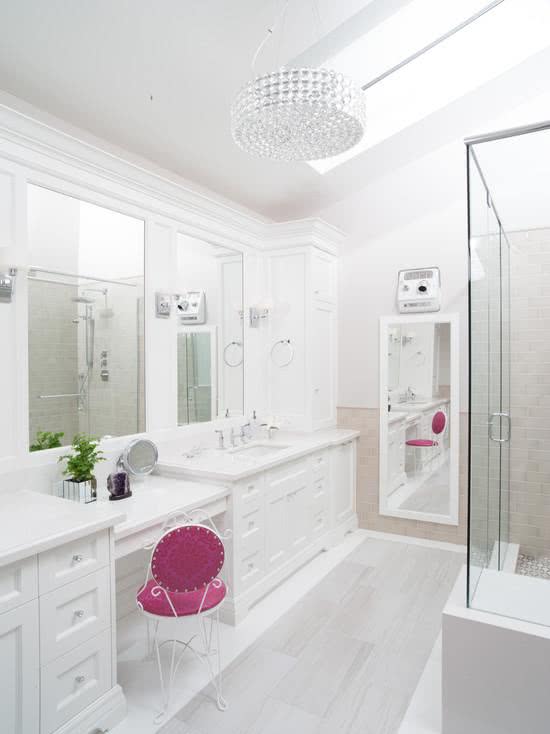 Penteadeira no banheiro branco com poltrona rosa