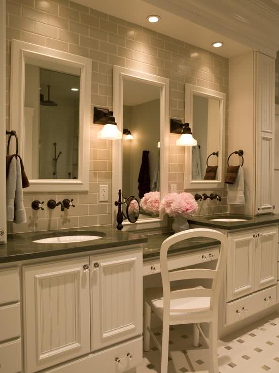 Penteadeira junto a bancada do banheiro com três espelhos com moldura