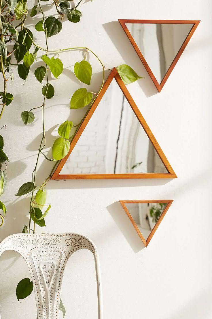 Conjunto de espelhos em formato triangular com moldura de madeira.