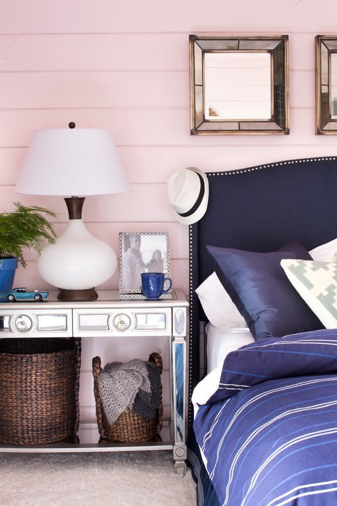 Linda combinação entre o rosa claro da parede e cama azul marinho. Detalhes cromados e espelhados nas molduras e no aparador