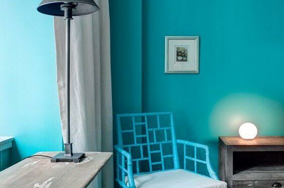 The apartment of Rhonda Weinman, with its newly turquoise color scheme, New York, Jan. 5, 2014. With a Chinese Chippendale chair and Dioscuri light, right, the sitting area furniture softens the wall color. (Bruce Buck/The New York Times.)
