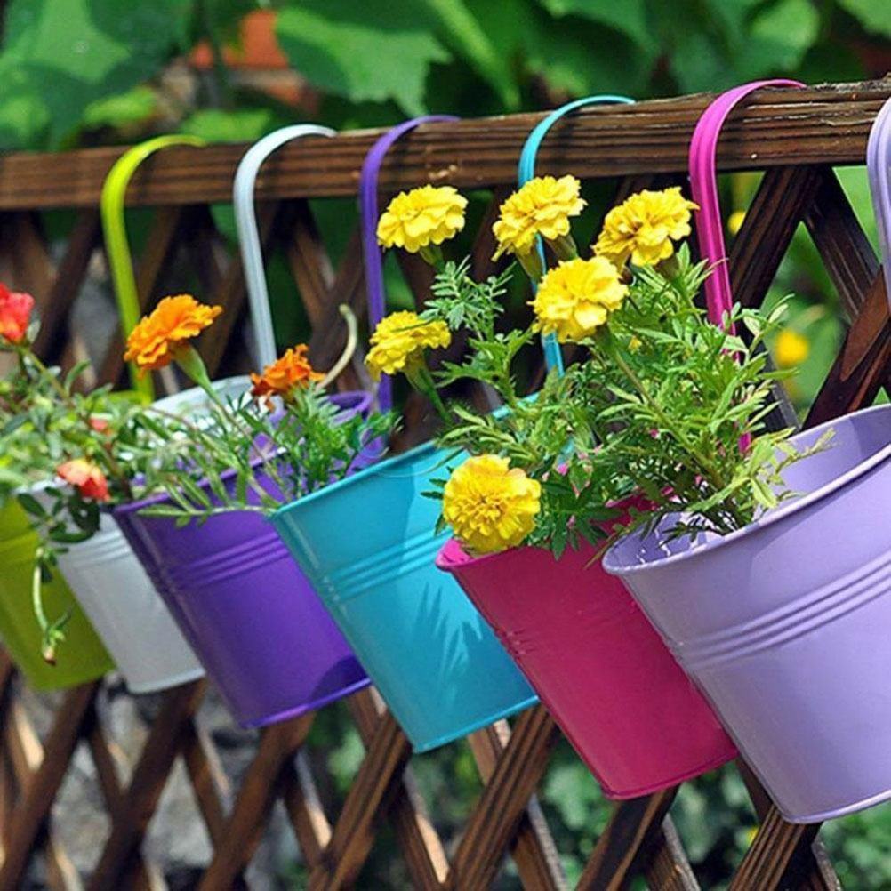 Para deixar o jardim mais vibrante, insira as flores em baldes metálicos coloridos.