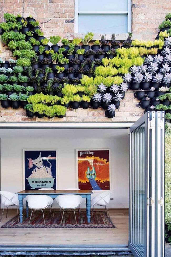 The facade of this house received vases of different colors and species to form the vertical garden.