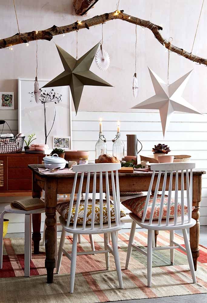 Em um ambiente rústico as estrelas de natal penduradas em um galho fazem toda a diferença na decoração da mesa de natal