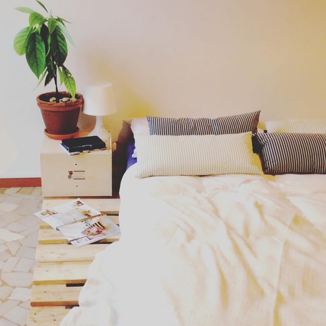 Cama de pallet baixa com vaso decorativo no criado-mudo