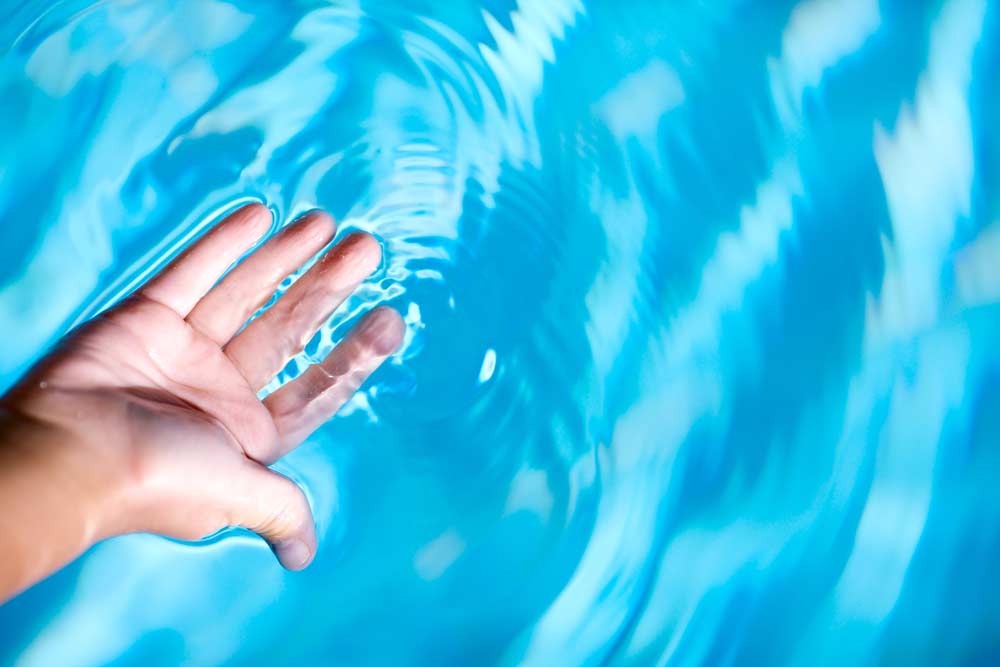 Como limpar piscina: mãos na água
