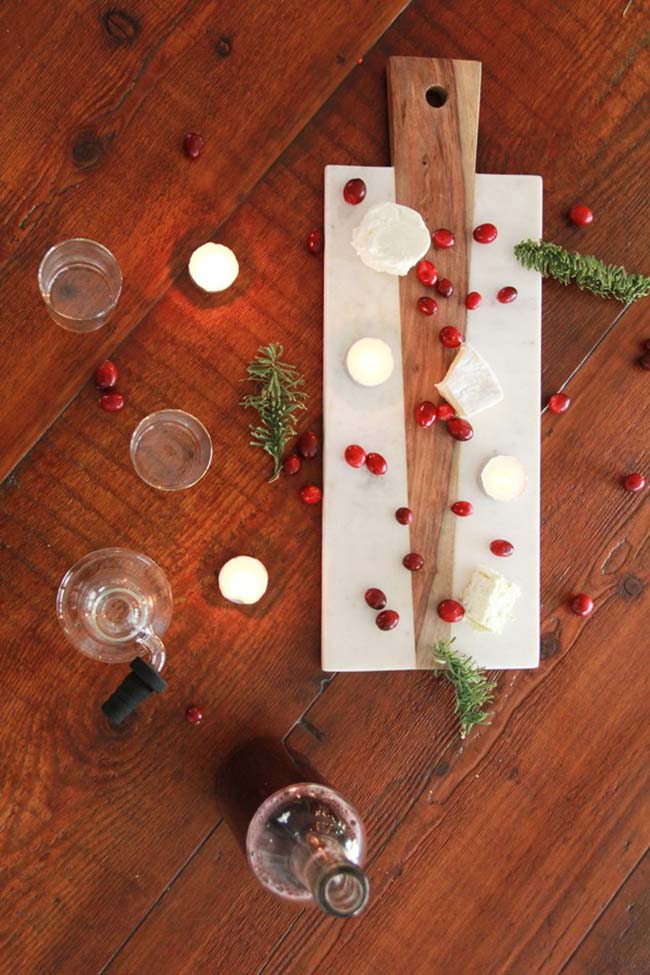 Decoração de mesa de Natal natural com galhos de alecrim, romãs, queijos e velas