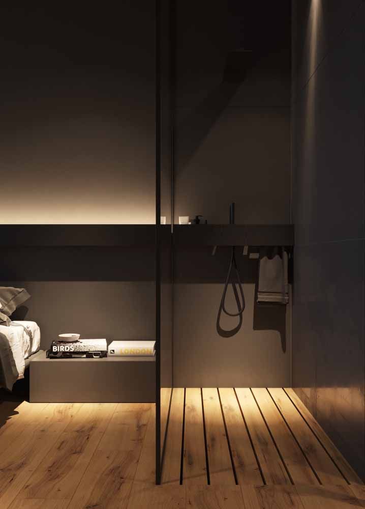 Quarto e banheiro integrados com a mesma cor – preta – nas paredes e o mesmo piso de madeira