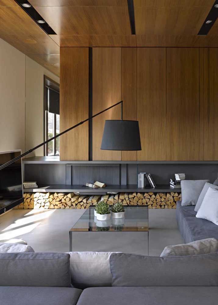 O revestimento de madeira e o sofá grande de canto são um convite para ficar nessa sala