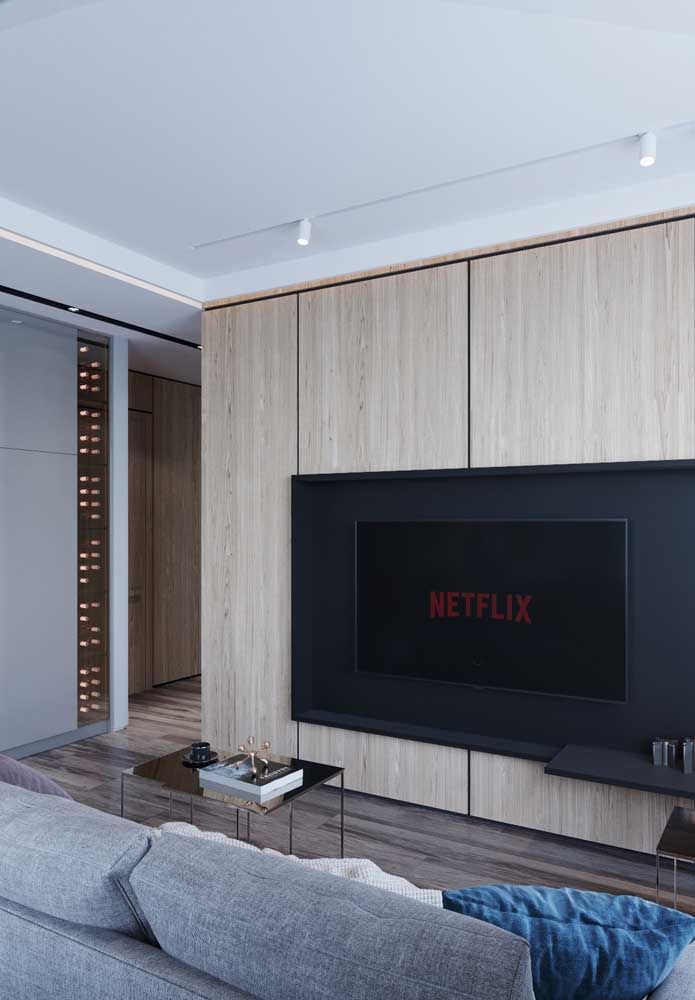 O painel para TV funciona também como um armário embutido; a ausência de puxadores revela a estética clean da sala