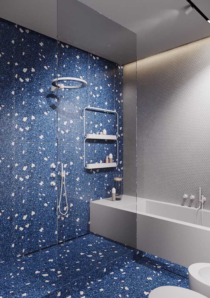 In this luxury bathroom, the bath area has glass doors and a blue coating that extends to the floor