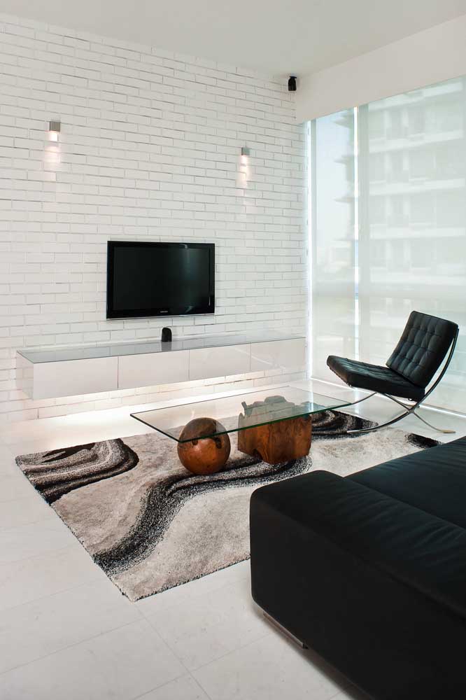 A sala moderna e minimalista optou por um rack branco com iluminação embutida