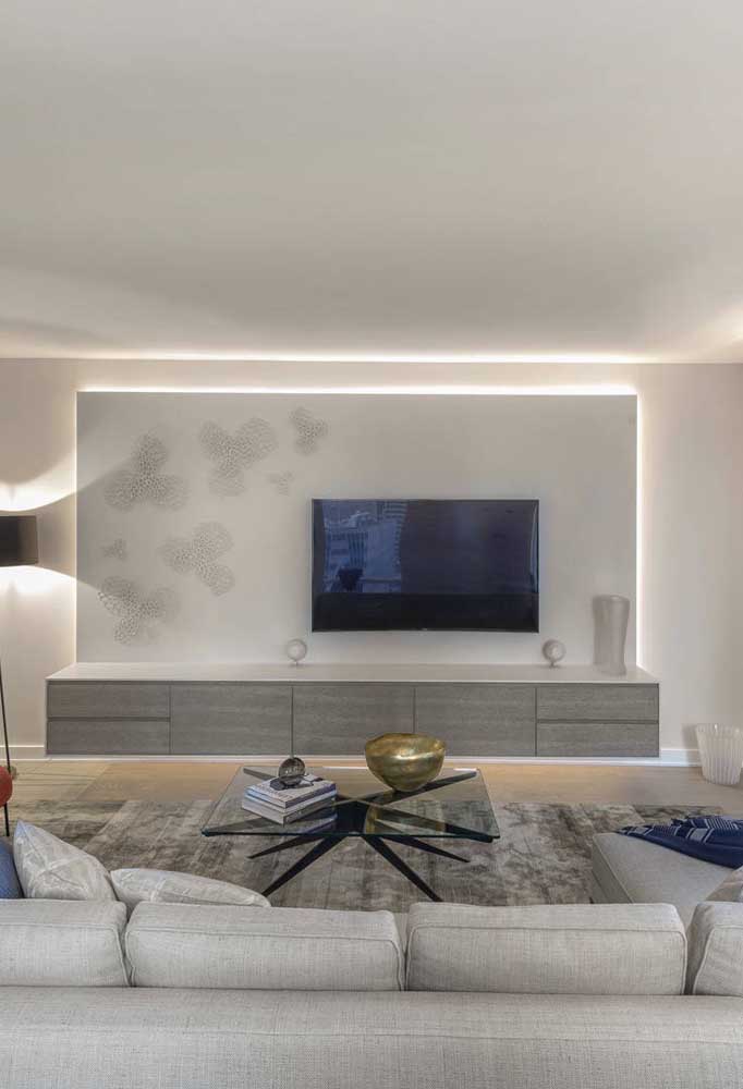 Rack suspenso em cinza com painel: a iluminação atrás do móvel traz profundidade a sala de estar