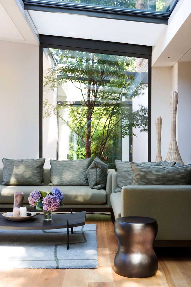 Sala de estar com jardim de inverno; o vidro delimita os ambientes