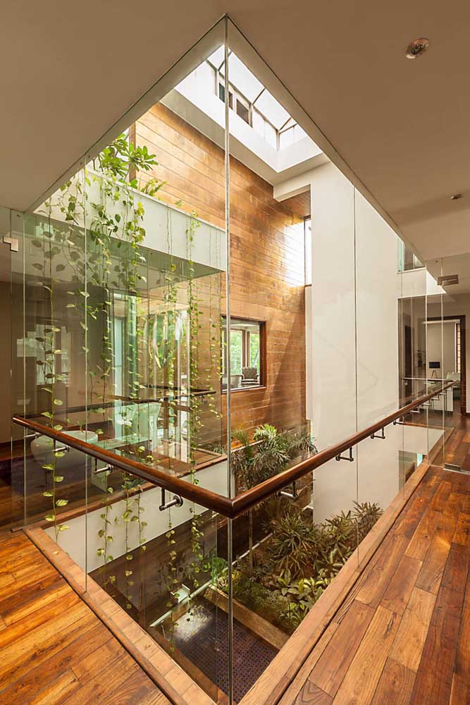Essa casa sobrado apostou em paredes de vidro para garantir a apreciação do jardim de inverno onde quer que as pessoas estejam