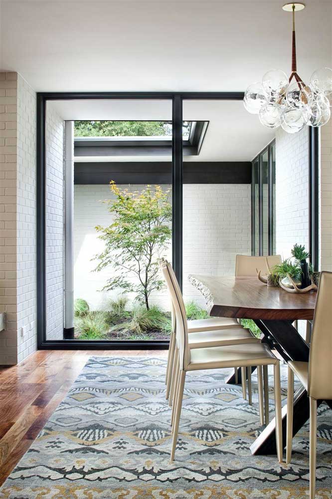 Jardim de inverno para sala de jantar; destaque para o friso preto que emoldura a porta de vidro entre os ambientes