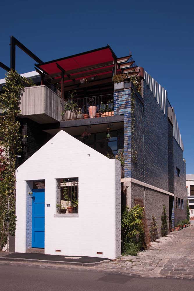 Casa de alvenaria pequena com dois pavimentos e terraço aberto com acabamento em cerâmica de tijolos coloridos