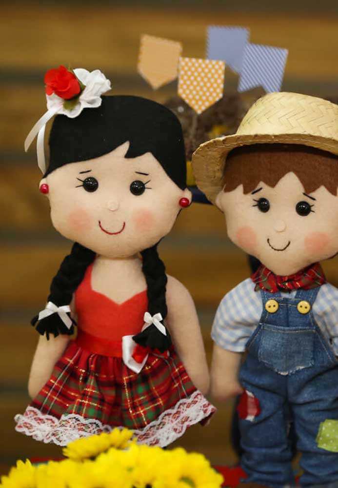 Na decoração de festa junina infantil use alguns bonecos com trajes juninos para enfeitar o local.
