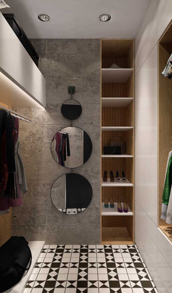 Decoração moderna e estilosa dentro do closet pequeno. Destaque para o conjunto de espelhos e para a parede de concreto aparente