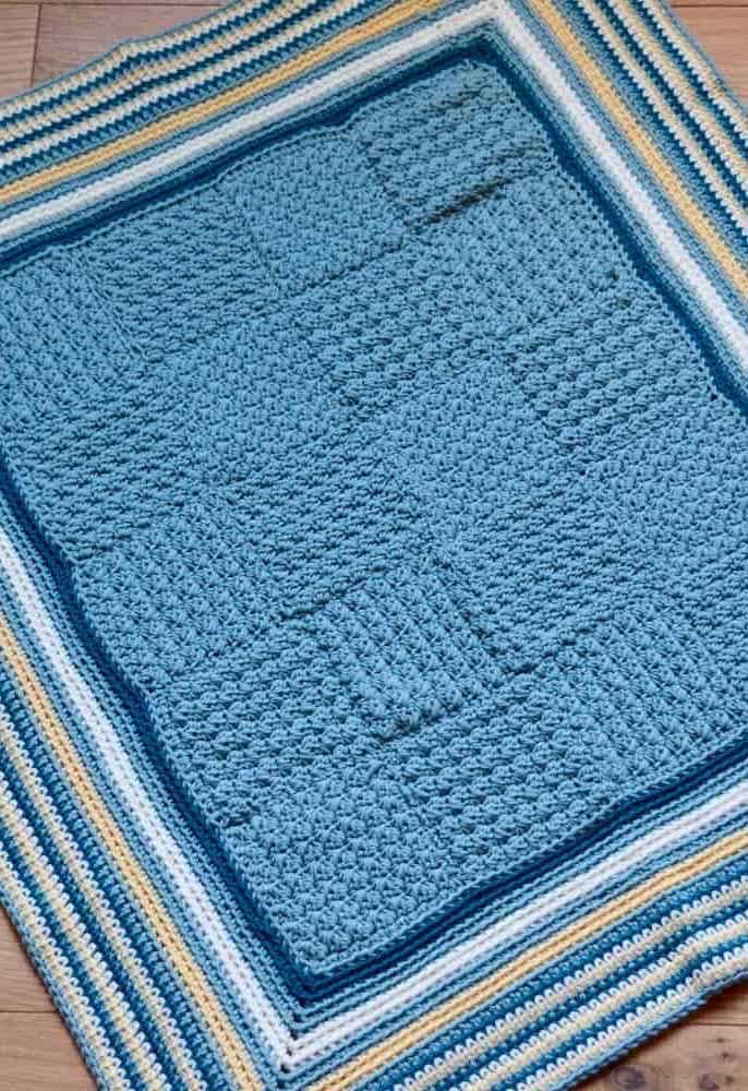 Tapete quadrado de crochê azul claro com bordas em diferentes faixas de cores.