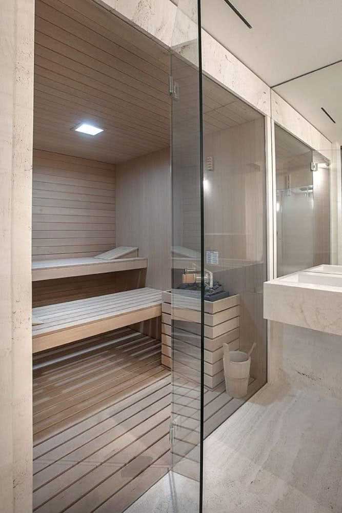 Já este banheiro com sauna tem o mármore instalado no piso e na parede.