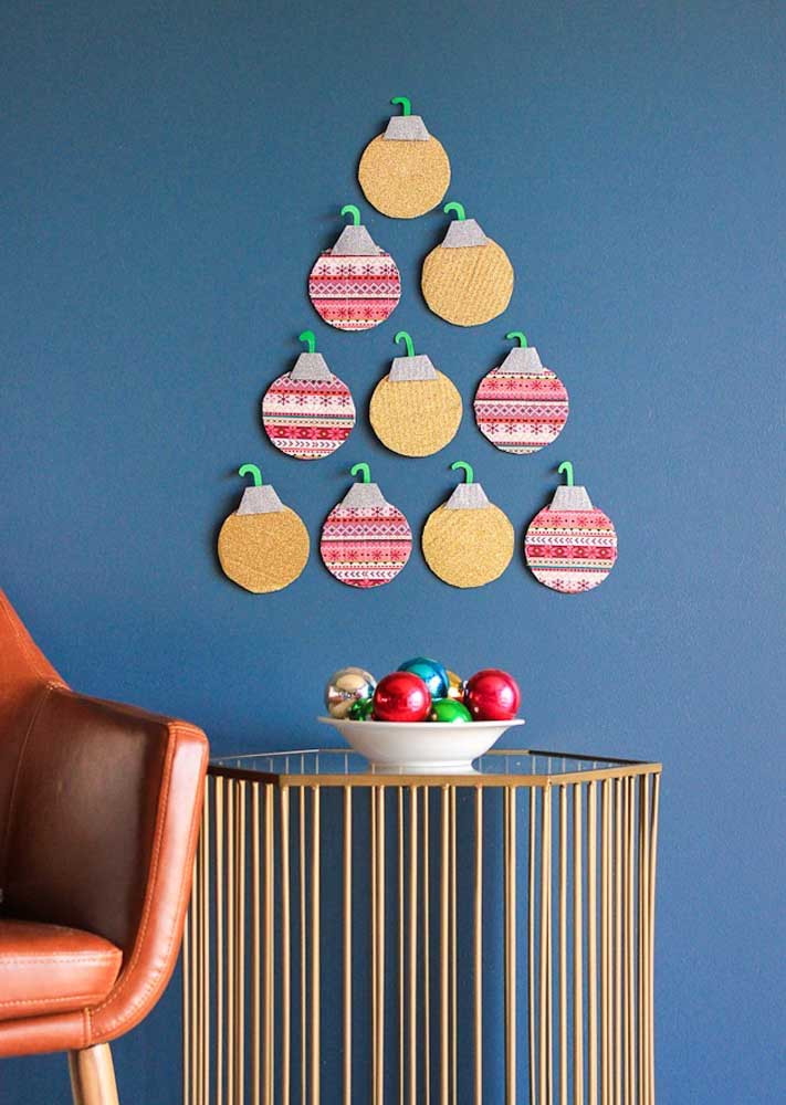 Árvore de Natal feitas com bolas natalina de feltro fixadas na parede.