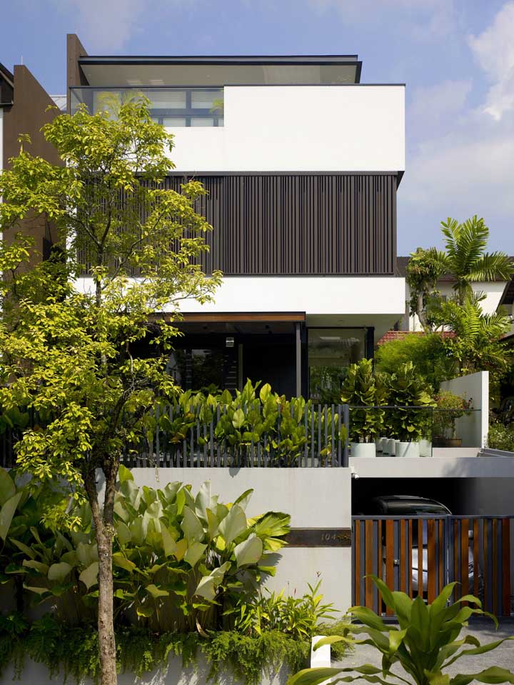 Casa linda e grande com garagem e um belo projeto paisagístico na fachada.