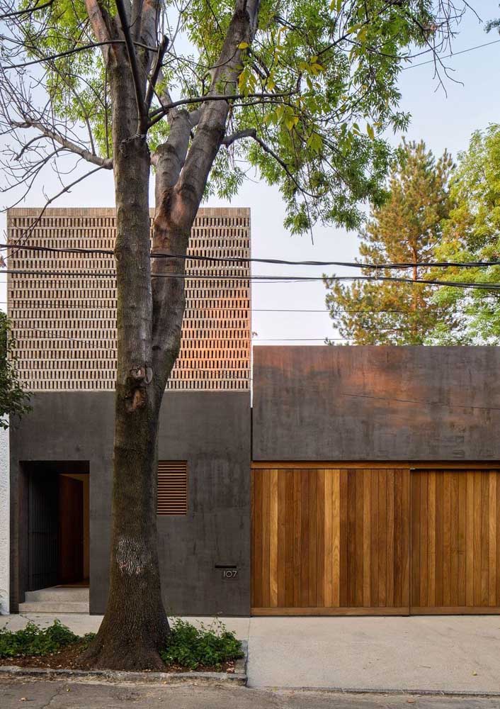 Fachada de casa com concreto aparente e portão de madeira.