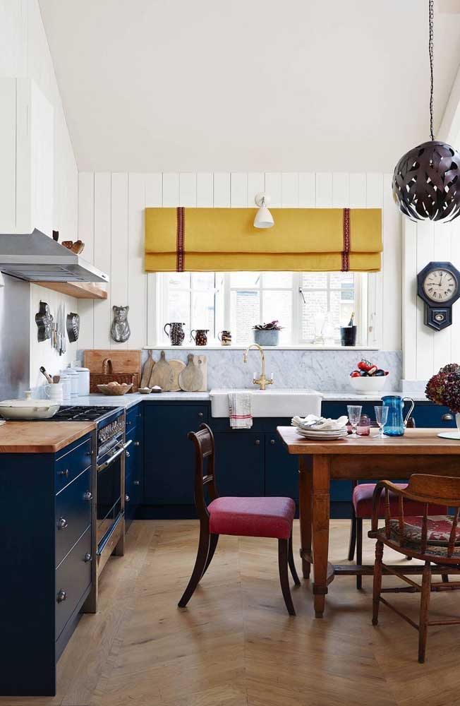 Cozinha vintage com armário em azul marinho e cortina mostarda na janela próxima a pia da cozinha.