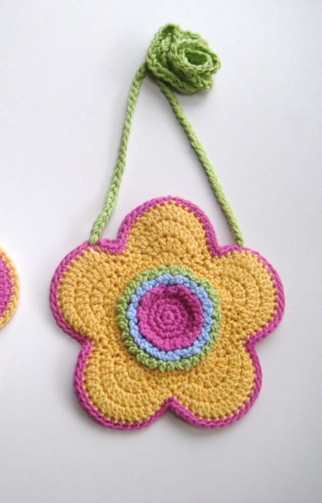 Flor de crochê colorida para pendurar feita com barbante verde, rosa, azul claro e amarelo.