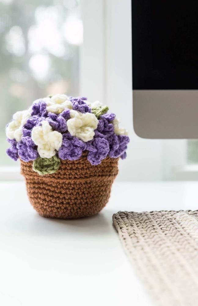 Outro vaso realista de crochê com flores roxas e brancas.