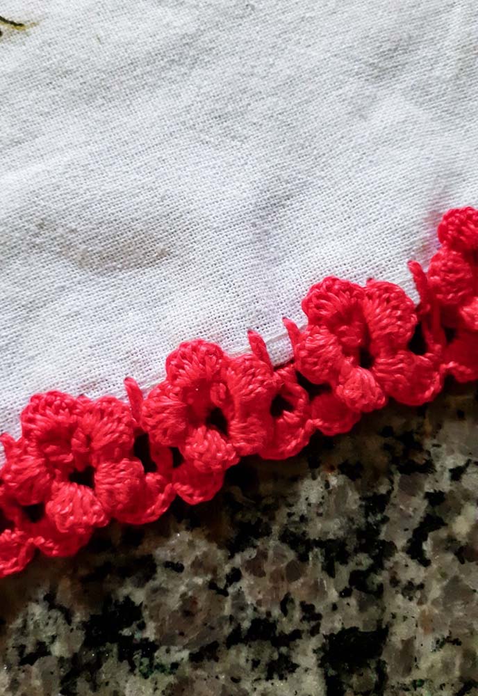 Bico de crochê vermelho para pano de prato branco.