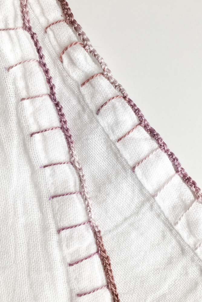 Lilás e branco em bico de crochê em degradê para uma peça de tecido branco.