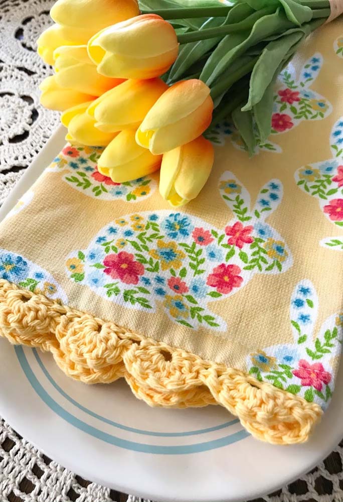 Toalha de tecido estampada com lindos coelhinhos e bico de crochê amarelo.