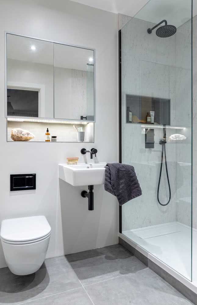 Banheiro simples cinza com chuveiro metálico preto.