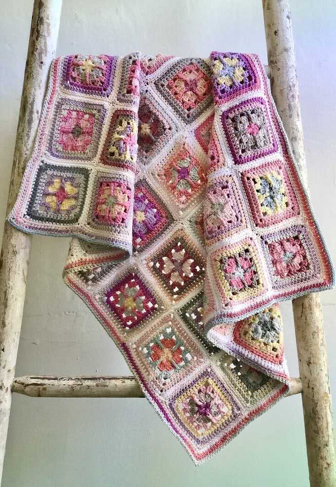 Decoração de tapete de crochê com flores em quadrados coloridos.