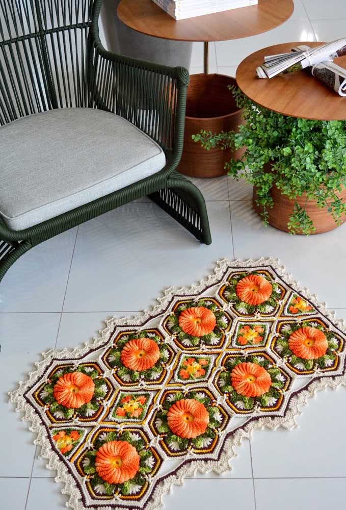Peça retangular de crochê com flores em alto-relevo.