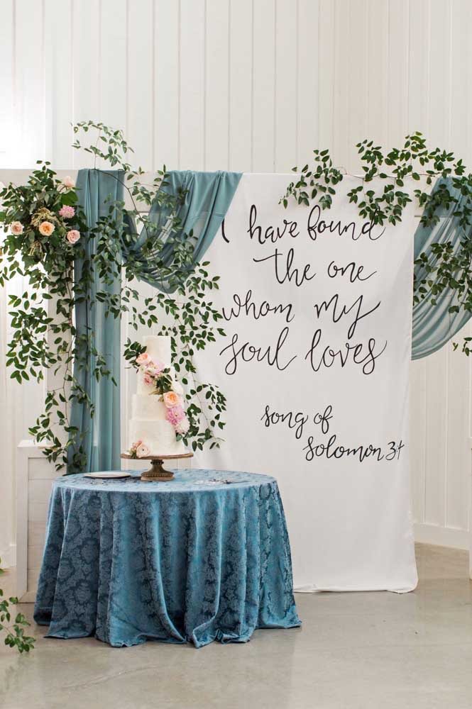 Mesa para bolo de casamento com painel de tecido para tema na cor azul.