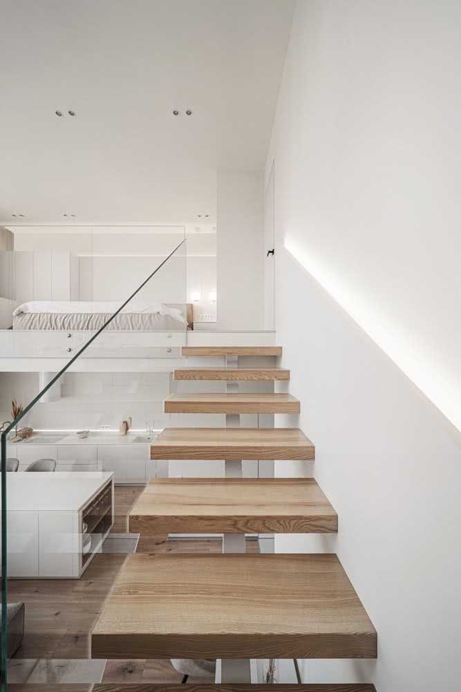 Escada flutuante de madeira com base metálica sob os degraus e lateral de vidro