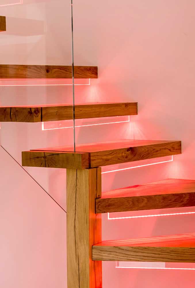 Escada flutuante de madeira com iluminação LED embutida em tons delicados de rosa