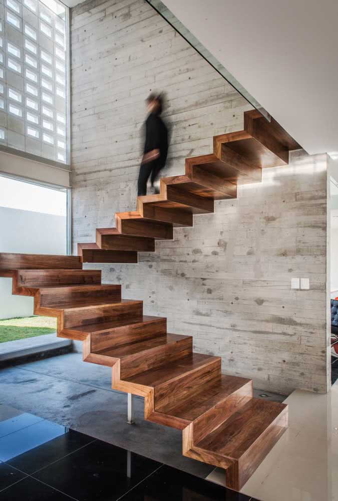 O belo contraste entre a escada flutuante de madeira e a parede de concreto aparente
