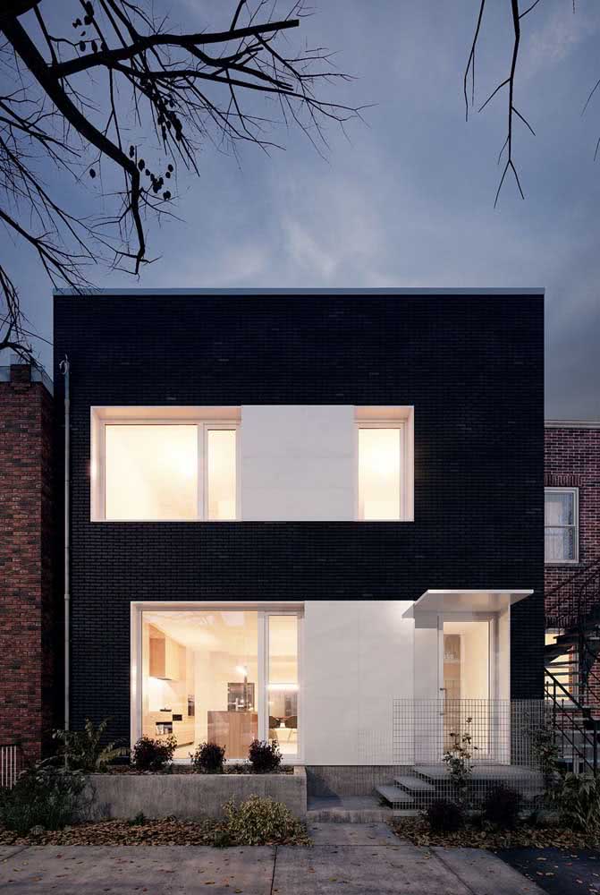 Casa moderna com fachada toda em preto. Destaque para o uso dos vidros que traz leveza para composição