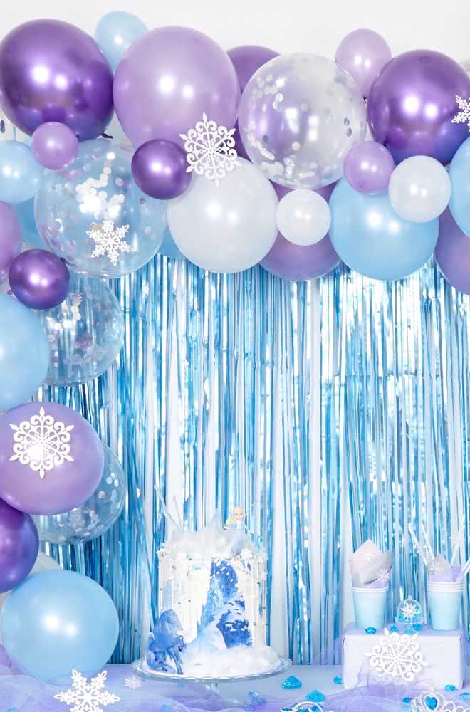 Detalhe da mesa Frozen com balões e fitas no fundo.