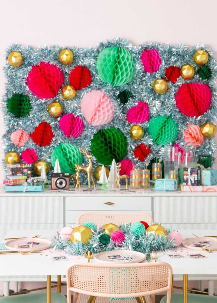 Ideia de buffet decorado de Natal com painel montado com fitas e bolas colmeia.