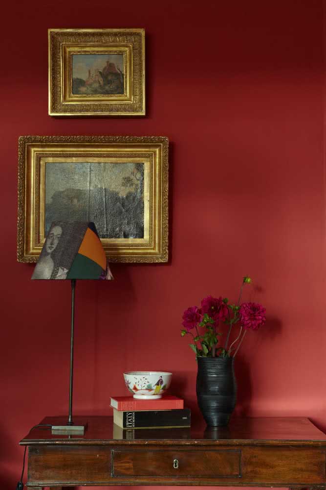 Que tal uma parede vermelha para exibir os quadros clássicos de moldura dourada?