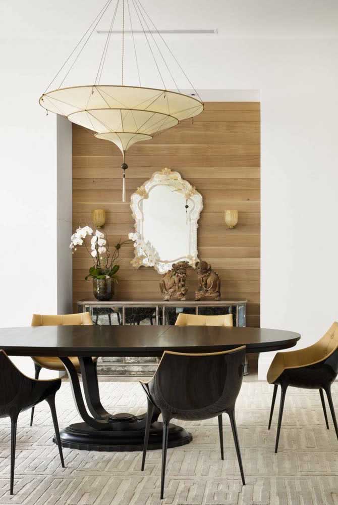 Olha esse contraste: espelho veneziano na sala de jantar moderna. O painel de madeira criou um fundo lindo