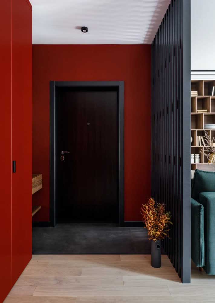 A pintura vermelha e o painel isolam e delimitam o hall de entrada simples do restante dos ambientes