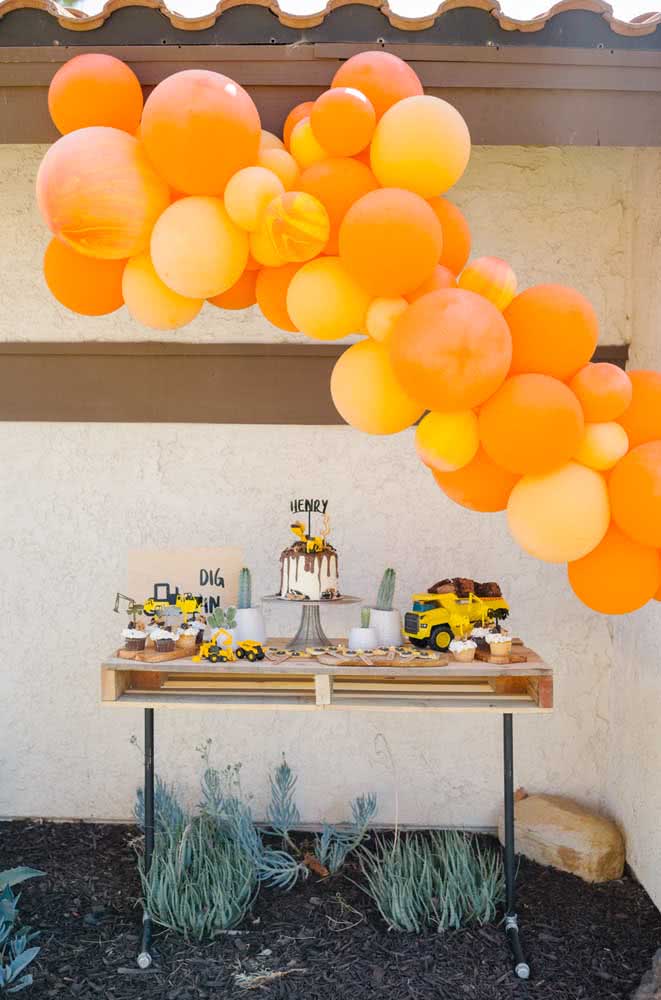 Decoração com balões laranjas para festa com tema trator.