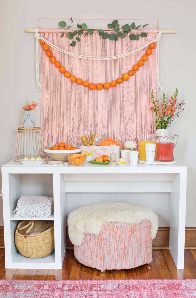 Mesa com cortina rosa rendada, doces e jarro com de sucos.
